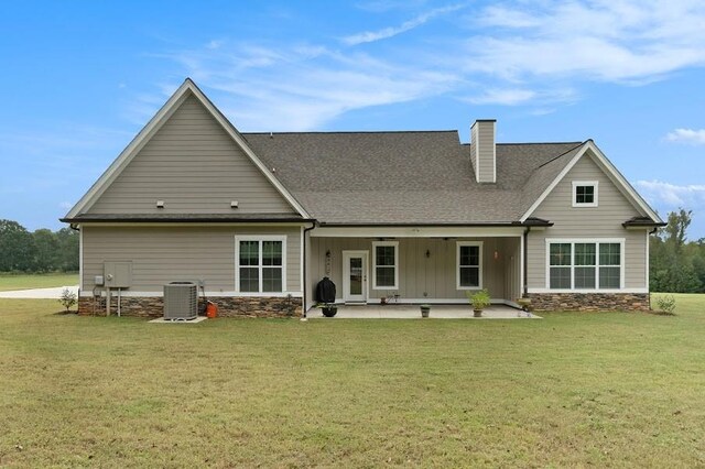 rear view of house featuring cooling unit, a lawn, and a patio area