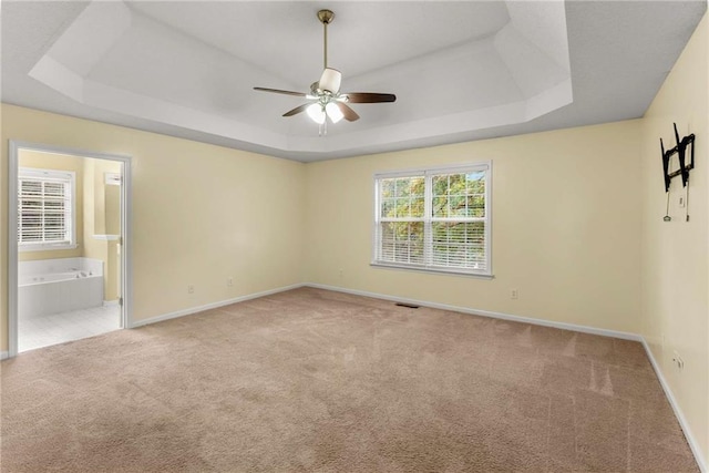 carpeted empty room with baseboards, visible vents, and a tray ceiling