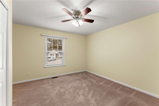 carpeted spare room with a textured ceiling, a ceiling fan, visible vents, and baseboards