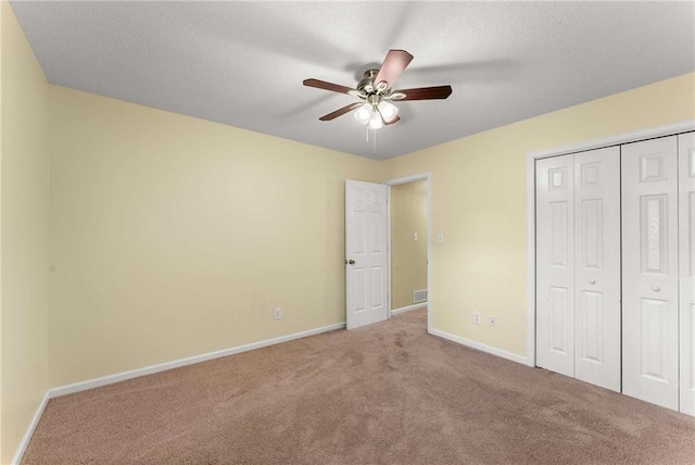 unfurnished bedroom with ceiling fan, a textured ceiling, carpet flooring, baseboards, and a closet