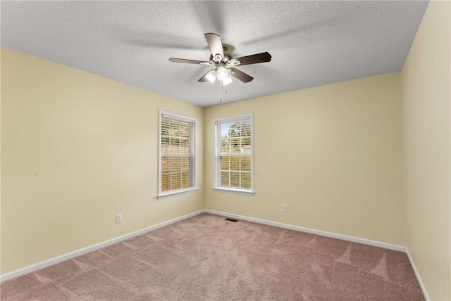 carpeted empty room with a ceiling fan, visible vents, a textured ceiling, and baseboards