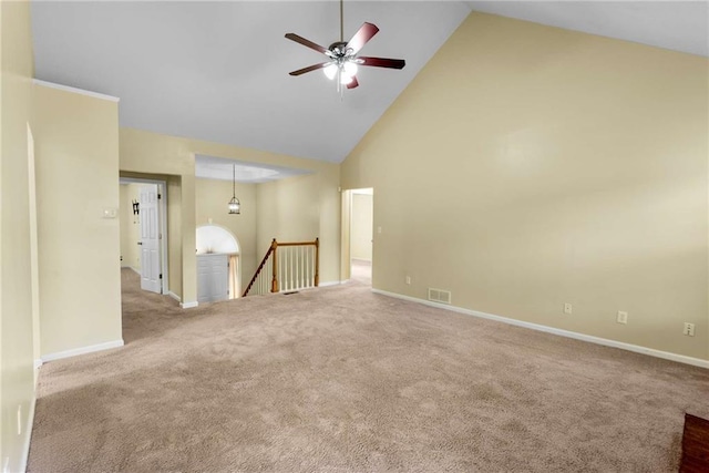 carpeted empty room featuring high vaulted ceiling, baseboards, visible vents, and ceiling fan