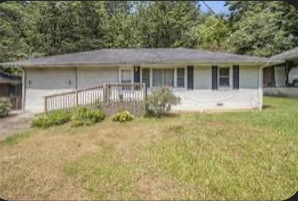 ranch-style house with a deck and a front yard