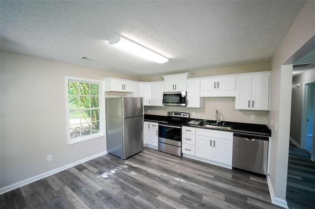 212 Cobb St, Cedartown, GA 30125 - kitchen with a textured ceiling, visible vents, dark wood finished floors, a sink, and stainless steel appliances