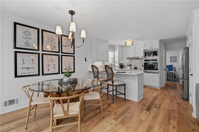 6160 Lake Lanier Heights Rd, Buford, GA 30518 - kitchen featuring stainless steel appliances, under cabinet range hood, a peninsula, and white cabinetry