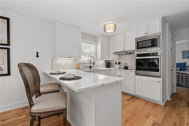 6160 Lake Lanier Heights Rd, Buford, GA 30518 - kitchen with appliances with stainless steel finishes, a peninsula, under cabinet range hood, and tasteful backsplash