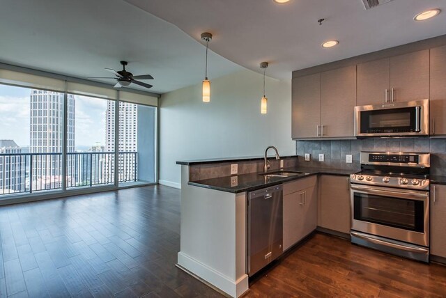 kitchen with decorative light fixtures, dark stone counters, appliances with stainless steel finishes, ceiling fan, and sink