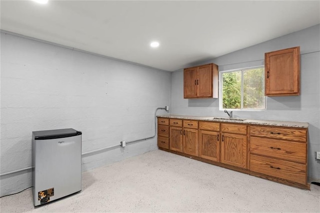 1245 Meriwether St, Griffin, GA 30224 - kitchen with a sink, brown cabinets, light countertops, fridge, and dark aggregate flooring