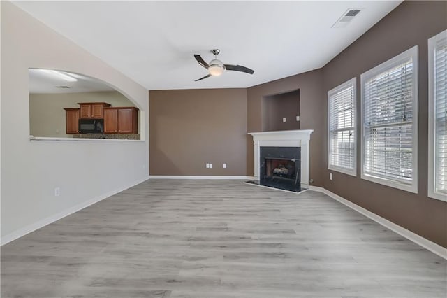 unfurnished living room featuring a high end fireplace, ceiling fan, and light hardwood / wood-style flooring