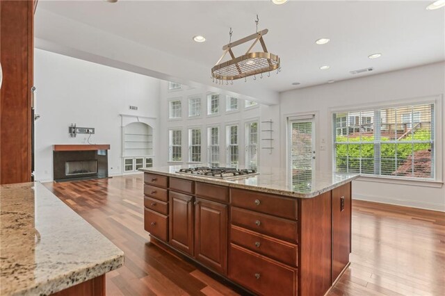 4540 Hastings Dr, Cumming, GA 30041 - kitchen with wood finished floors, a fireplace, stainless steel gas stovetop, light stone countertops, and recessed lighting