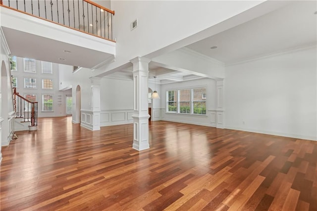 4540 Hastings Dr, Cumming, GA 30041 - unfurnished living room featuring ornate columns, a decorative wall, wood finished floors, stairs, and a high ceiling