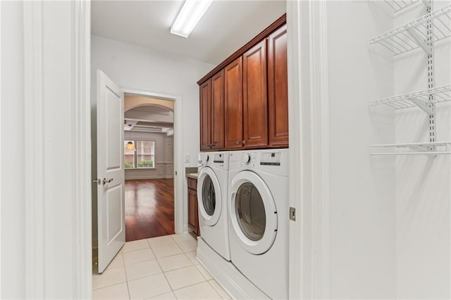 4540 Hastings Dr, Cumming, GA 30041 - laundry room featuring arched walkways, washer and dryer, cabinet space, and light tile patterned flooring