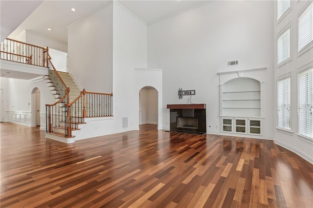 4540 Hastings Dr, Cumming, GA 30041 - unfurnished living room featuring arched walkways, a high ceiling, stairs, wood finished floors, and a fireplace