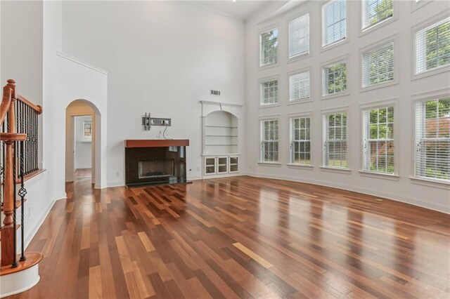 4540 Hastings Dr, Cumming, GA 30041 - unfurnished living room with a towering ceiling, wood finished floors, a fireplace, arched walkways, and baseboards