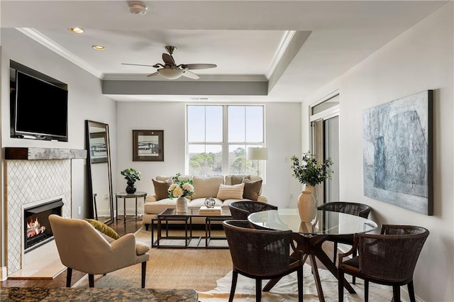 living area with a fireplace, wood finished floors, baseboards, and ornamental molding