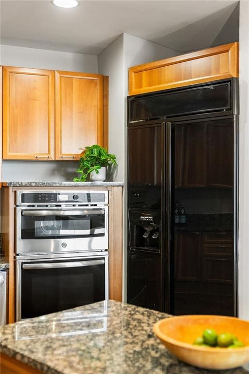 kitchen with light stone counters, stainless steel double oven, and built in refrigerator