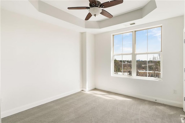 unfurnished room featuring a tray ceiling, baseboards, visible vents, and carpet floors