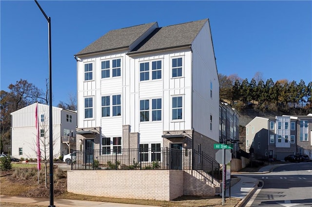 townhome / multi-family property with brick siding, a residential view, and roof with shingles