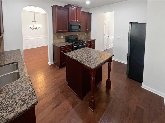 kitchen featuring a notable chandelier, a sink, arched walkways, appliances with stainless steel finishes, and dark wood-style flooring