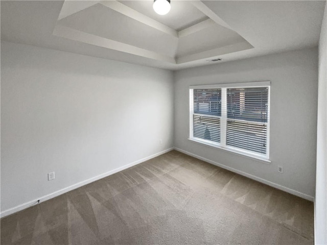 carpeted spare room with a tray ceiling and baseboards