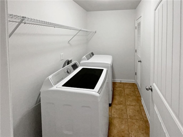 clothes washing area featuring light tile patterned floors, baseboards, separate washer and dryer, and laundry area