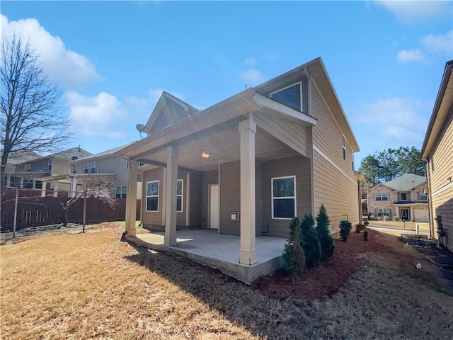 rear view of property featuring a yard, fence, and a patio area