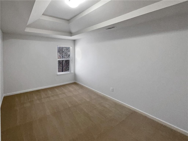 empty room with a tray ceiling, baseboards, carpet, and visible vents