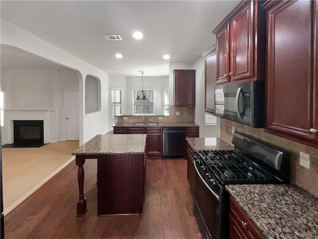 kitchen with visible vents, open floor plan, stainless steel appliances, a fireplace, and dark brown cabinets