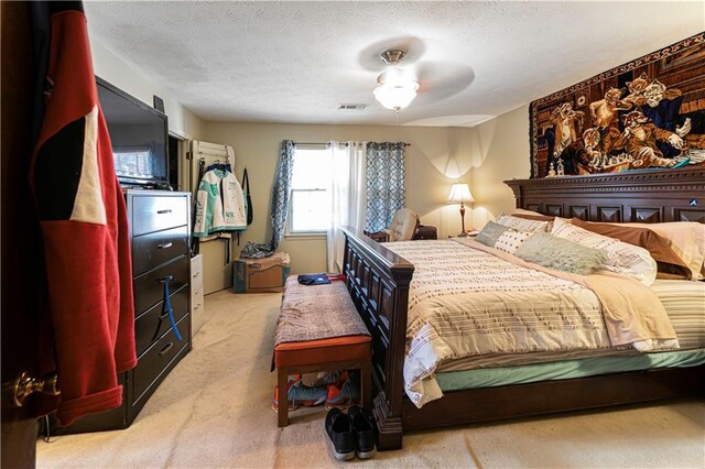 bedroom featuring ceiling fan, light colored carpet, and a textured ceiling