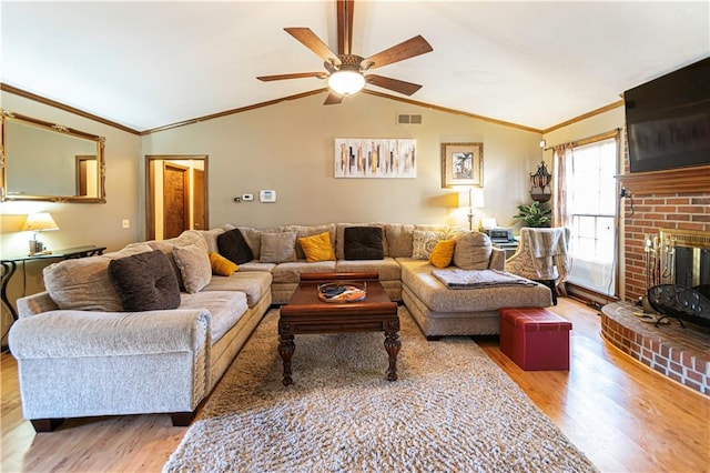 living room with hardwood / wood-style flooring, ceiling fan, lofted ceiling, and a brick fireplace