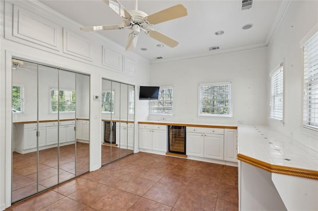 kitchen featuring white cabinetry, tile counters, ornamental molding, and beverage cooler