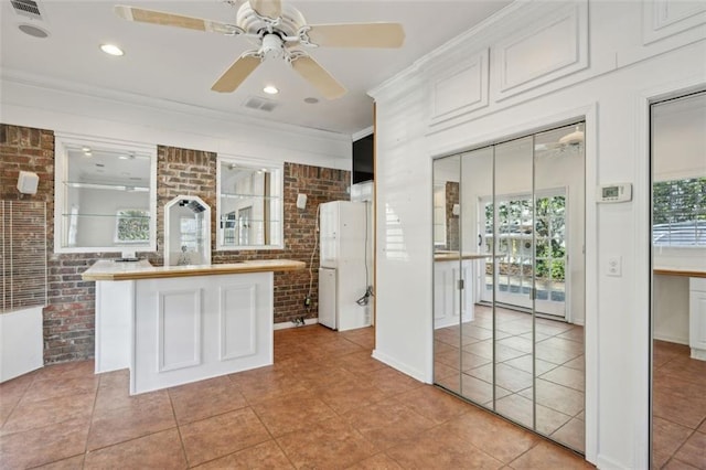 kitchen with a kitchen island, brick wall, butcher block counters, and white cabinets