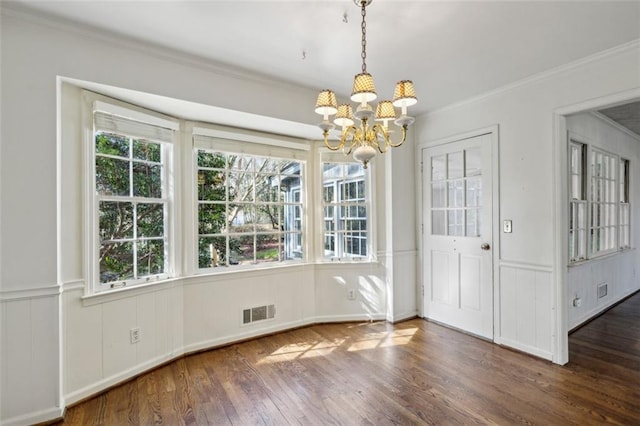 unfurnished dining area with an inviting chandelier, dark hardwood / wood-style flooring, and crown molding