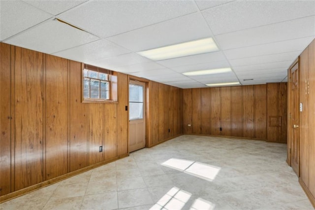 basement with a paneled ceiling and wooden walls