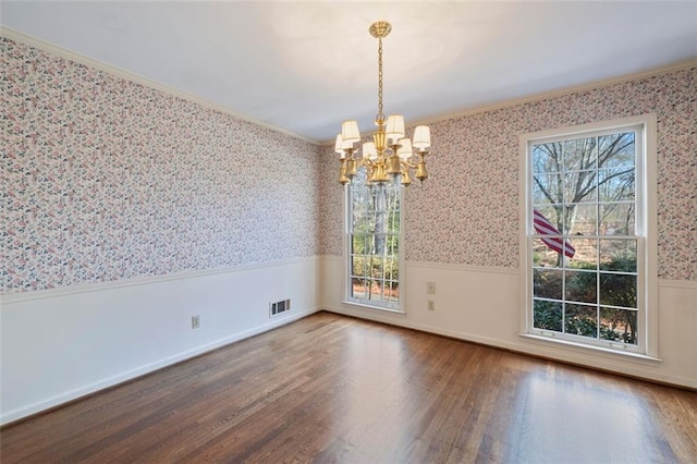 unfurnished dining area with ornamental molding, wood-type flooring, and a notable chandelier