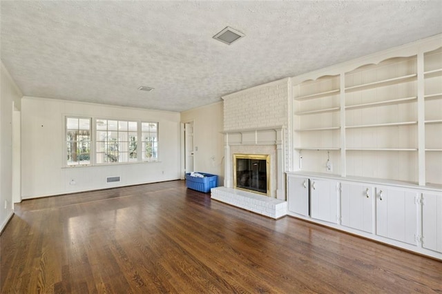 unfurnished living room with dark hardwood / wood-style flooring, a fireplace, built in features, and a textured ceiling