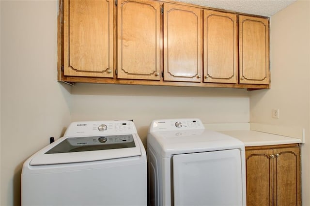 laundry room featuring washer and dryer, cabinets, and a textured ceiling