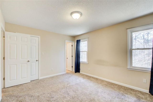 unfurnished bedroom with a textured ceiling and light carpet