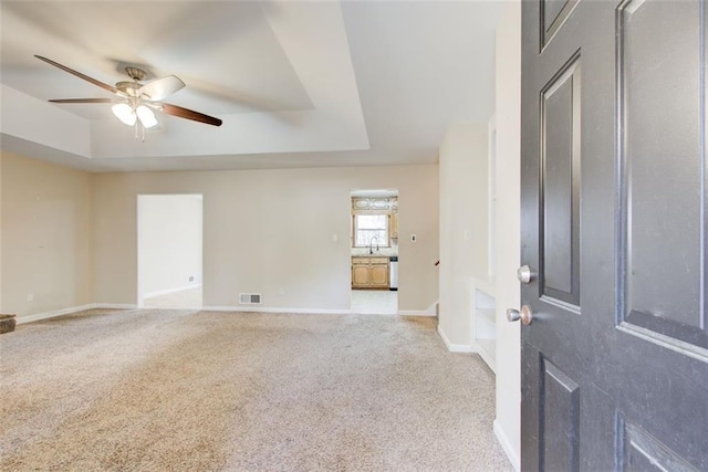 carpeted spare room with ceiling fan and a tray ceiling