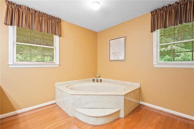 3436 Laurelwood Ct NE, Roswell, GA 30075 - bathroom with wood finished floors, a garden tub, and a textured ceiling