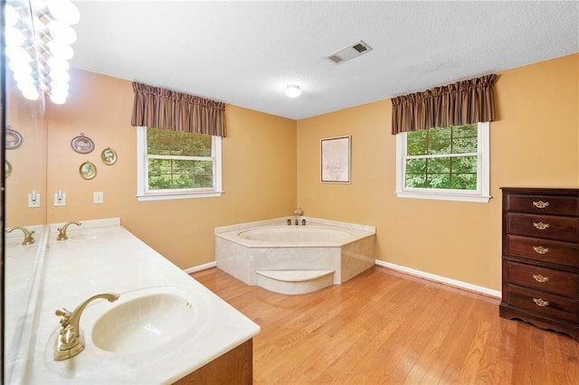 3436 Laurelwood Ct NE, Roswell, GA 30075 - bathroom featuring a garden tub, healthy amount of natural light, wood finished floors, double vanity, and a textured ceiling