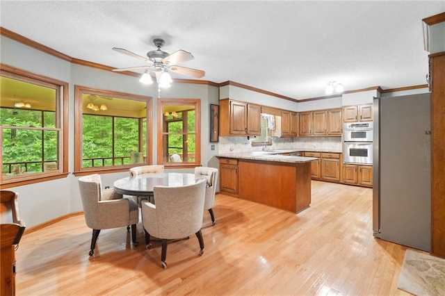 3436 Laurelwood Ct NE, Roswell, GA 30075 - kitchen featuring a peninsula, brown cabinetry, stainless steel appliances, light wood-style flooring, and decorative backsplash