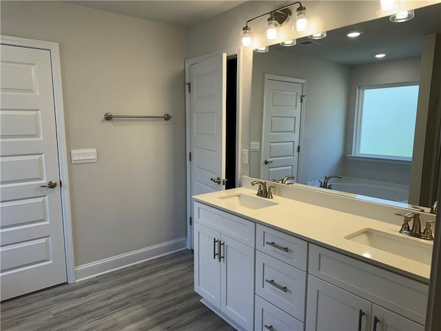 bathroom with a washtub, wood-type flooring, and vanity