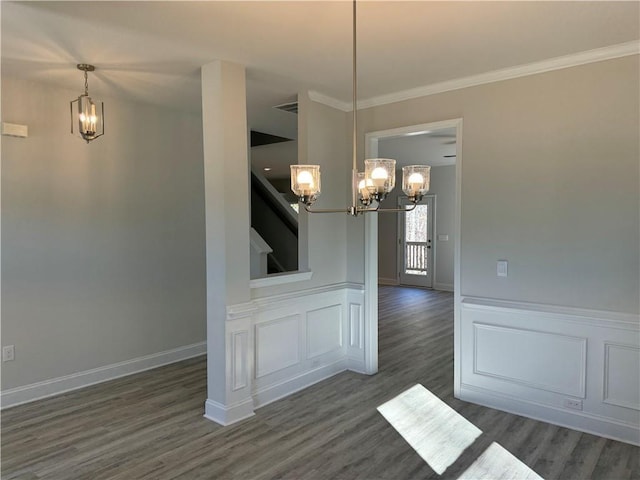 unfurnished dining area featuring dark hardwood / wood-style flooring, crown molding, and a notable chandelier