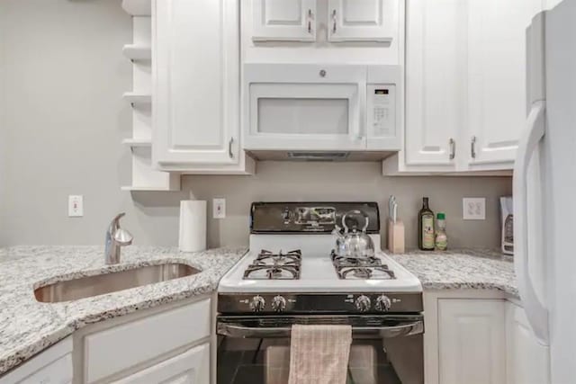 kitchen featuring white cabinetry, open shelves, white appliances, a sink, and light stone counters