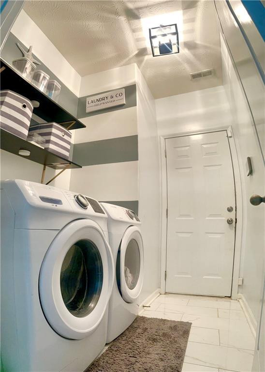 laundry area featuring a textured ceiling and independent washer and dryer