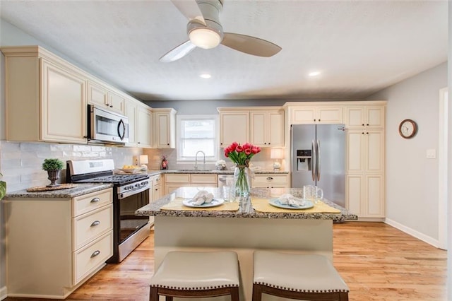 kitchen featuring a center island, a breakfast bar, sink, light hardwood / wood-style flooring, and appliances with stainless steel finishes