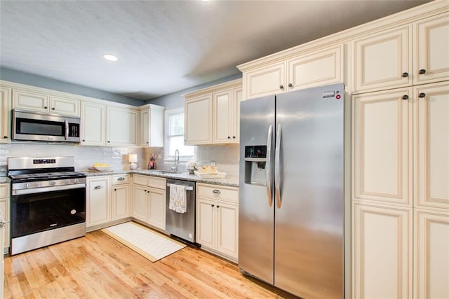 kitchen featuring appliances with stainless steel finishes, sink, light hardwood / wood-style floors, and cream cabinetry