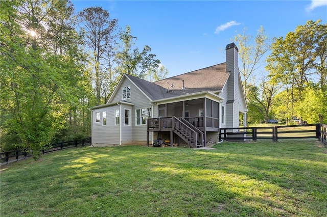 back of house featuring stairway, a lawn, a fenced backyard, and a sunroom