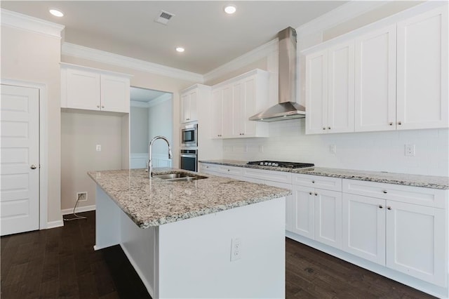 kitchen featuring a sink, wall chimney range hood, ornamental molding, dark wood finished floors, and appliances with stainless steel finishes